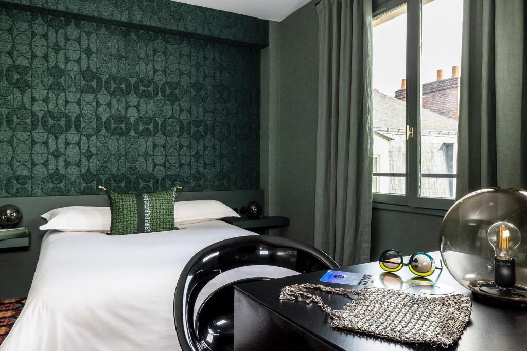 um quarto com uma cama, uma secretária e uma janela em L'Hôtel em Nantes