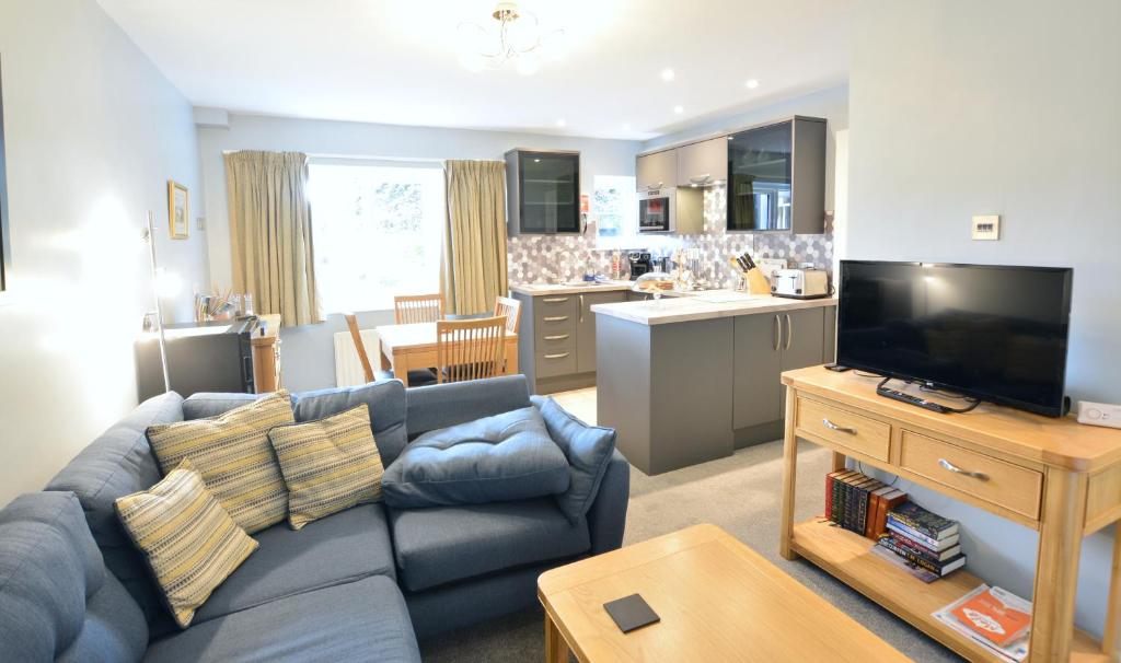 a living room with a blue couch and a kitchen at Chestnut Apartment in Bowness-on-Windermere