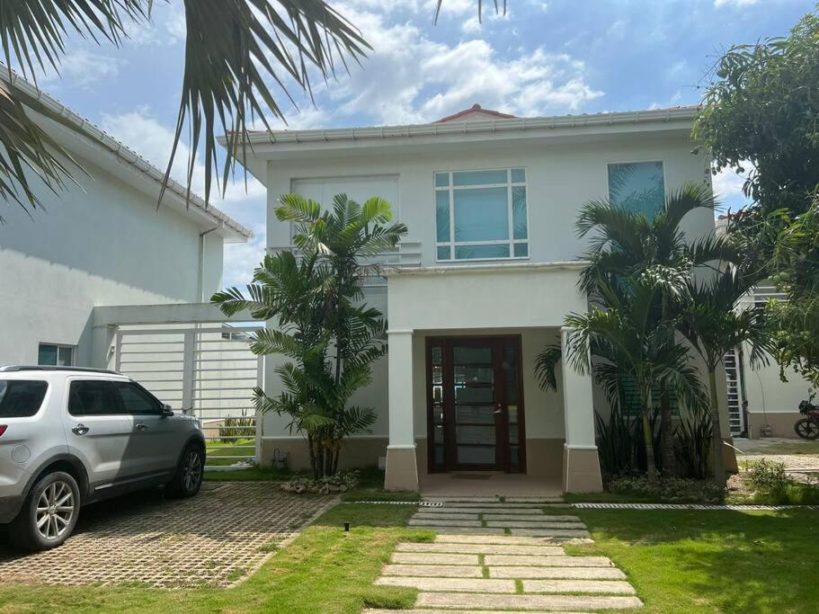 una casa blanca con un coche aparcado delante de ella en Casa Arcoíris: Espectacular casa en Cartagena con Acceso directo a la Playa, en Cartagena de Indias