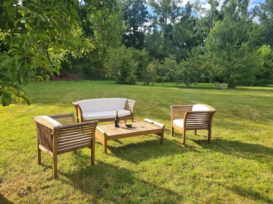 zwei Bänke und ein Tisch im Gras in der Unterkunft Belle maison avec grand jardin proche St Malo in Miniac-Morvan