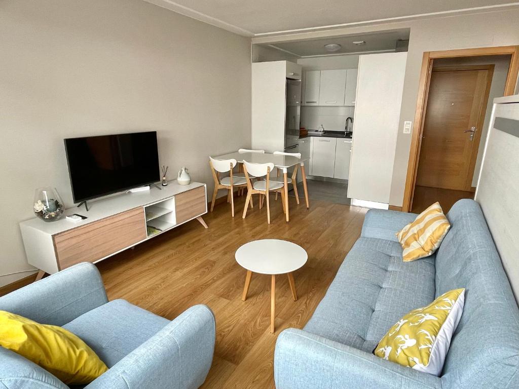 sala de estar con sofá azul y TV en Estudio céntrico 1 con terraza y parking privado, en Ourense