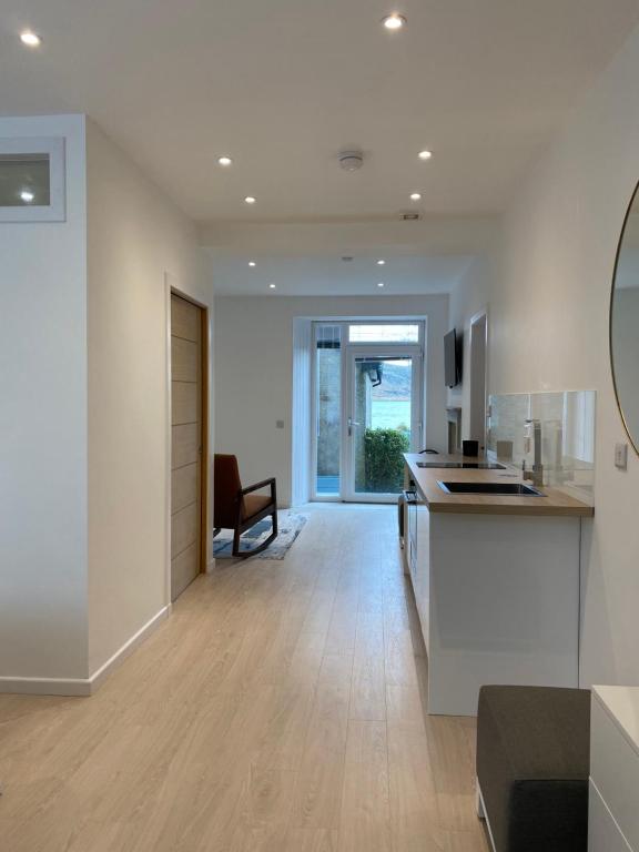 a kitchen and living room with white walls and wood floors at Hugmish in Tighnabruaich