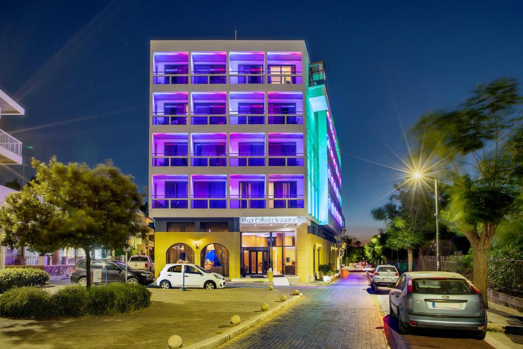 un grand bâtiment avec des lumières roses et violettes sur lui dans l'établissement Alexandra Hotel&Apartments, à Kos