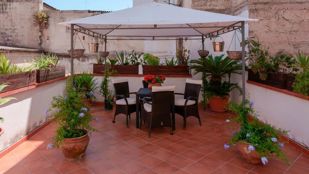 patio con tavolo e sedie sotto un ombrellone bianco di B&B Il Melograno Taranto a Taranto