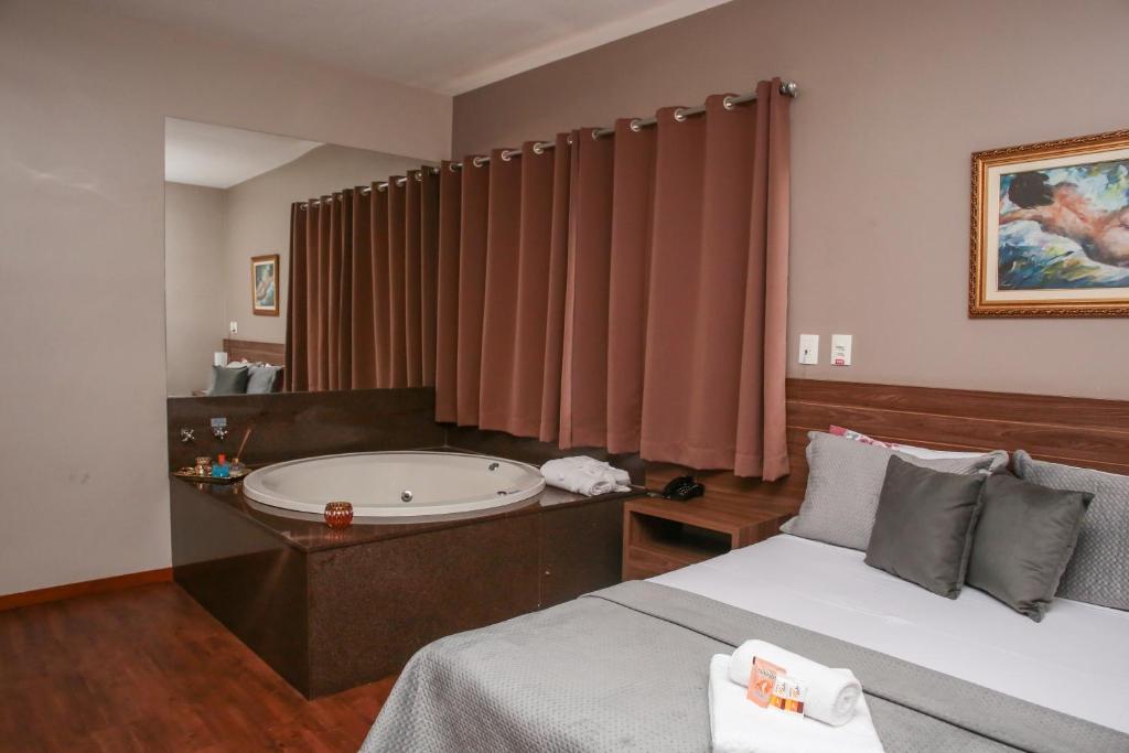 a bedroom with a bath tub and a bed at CAMBRAIA HOTEL ARCOS in Arcos
