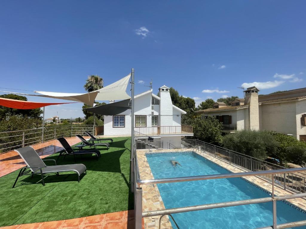 a house with a swimming pool and a patio with chairs at Villafavorita Casa Rural in Lorca