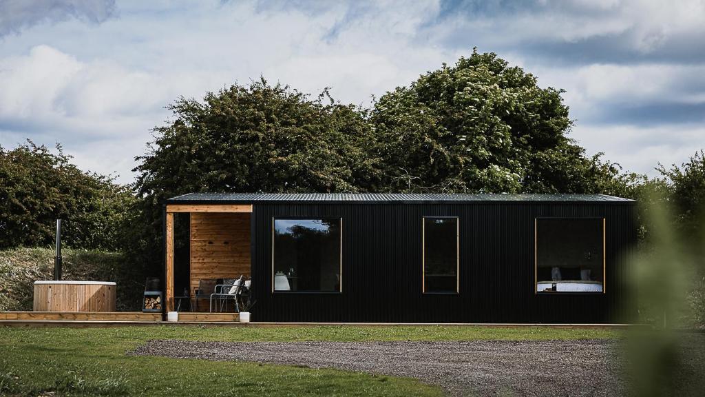 a black tiny house on a grass field at Off the Track Getaway, Luxury Lodge in Crail