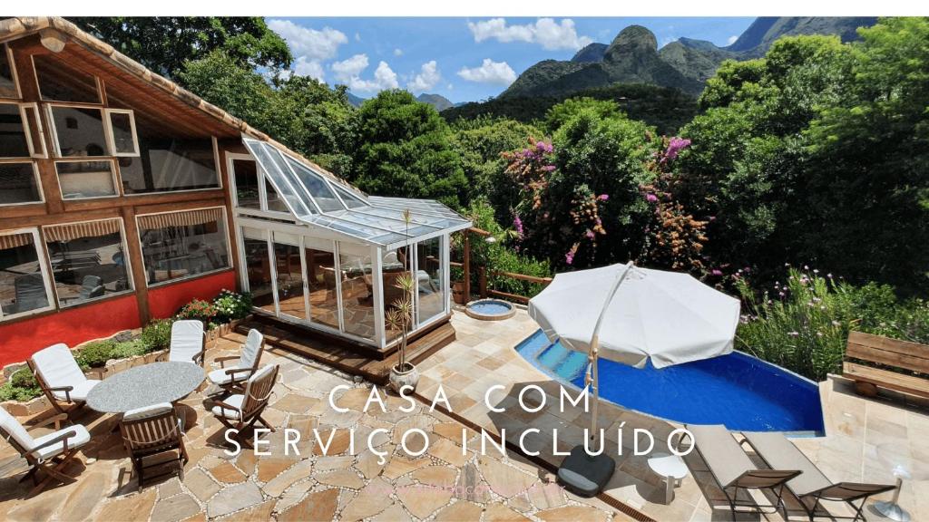uma vista exterior de uma casa com um pátio e uma piscina em Casa Maria Comprida Araras, serviço incluído, 5 quartos, piscina e área gourmet em Petrópolis