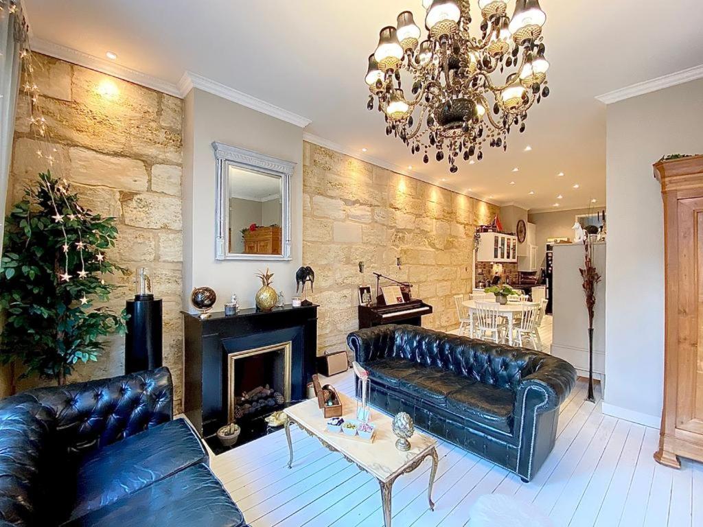 a living room with black leather furniture and a chandelier at Grand Appartement Haussmanien de Standing avec Jacuzzi Terrasse et Parking en Hyper Centre in Bordeaux