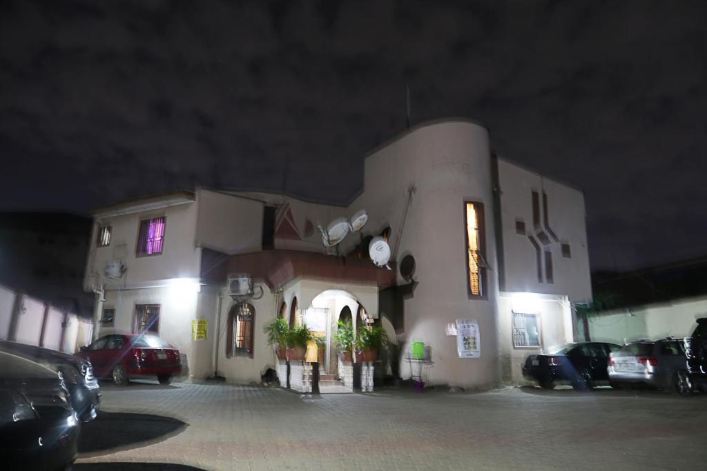a building with cars parked in a parking lot at night at CLASS COTTAGE in Ikeja