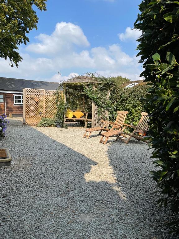 two wooden chairs sitting in a gravel yard at Holmdale Holiday Cottages in Rye