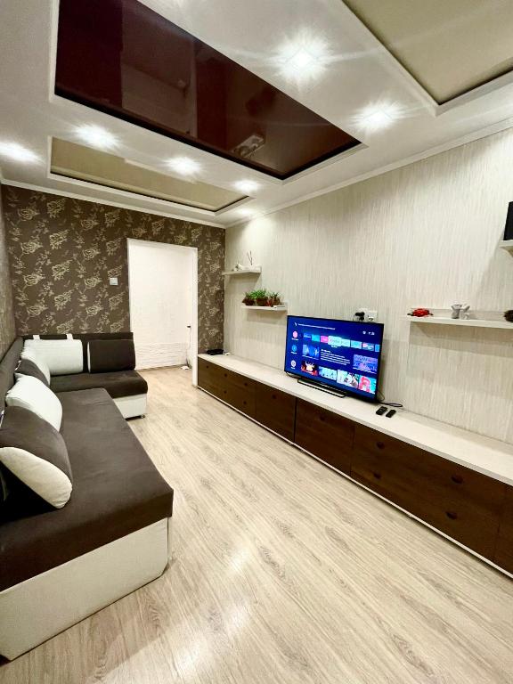 sala de estar con sofá y TV de pantalla plana en Роскошные апартаменты в центре, en Temirtaū