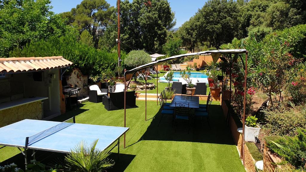 een tuin met een tafel en een zwembad op de achtergrond bij La Villa Poupée in Grambois