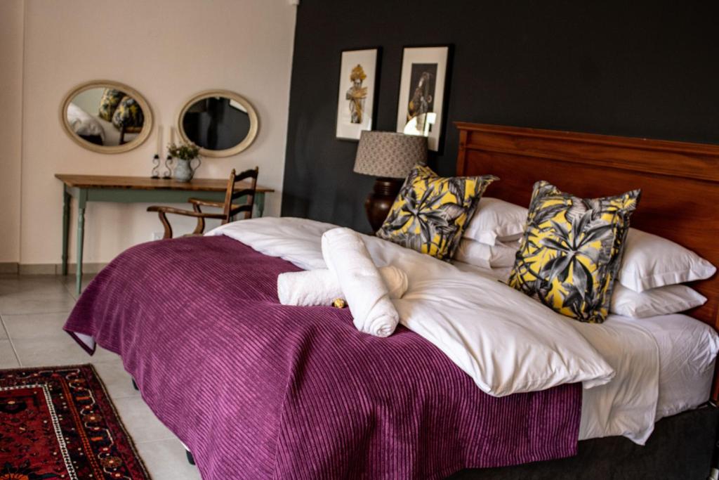 1 dormitorio con 1 cama grande con manta morada en 5 Rembrandt Guesthouse, en Somerset West