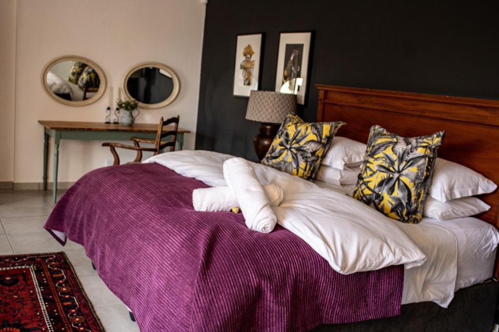 a bedroom with a large bed with a purple blanket at 5 Rembrandt Guesthouse in Somerset West