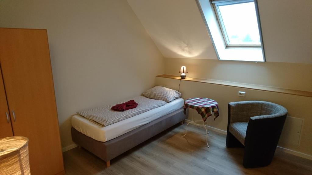 a small bedroom with a bed and a chair at Gasthaus Zur Hecke in Schönefeld