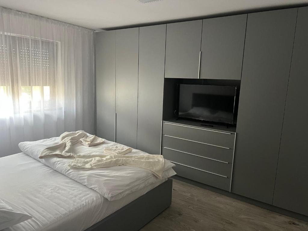a bedroom with a bed and a flat screen tv at Apartament 5ive in Tăşnad