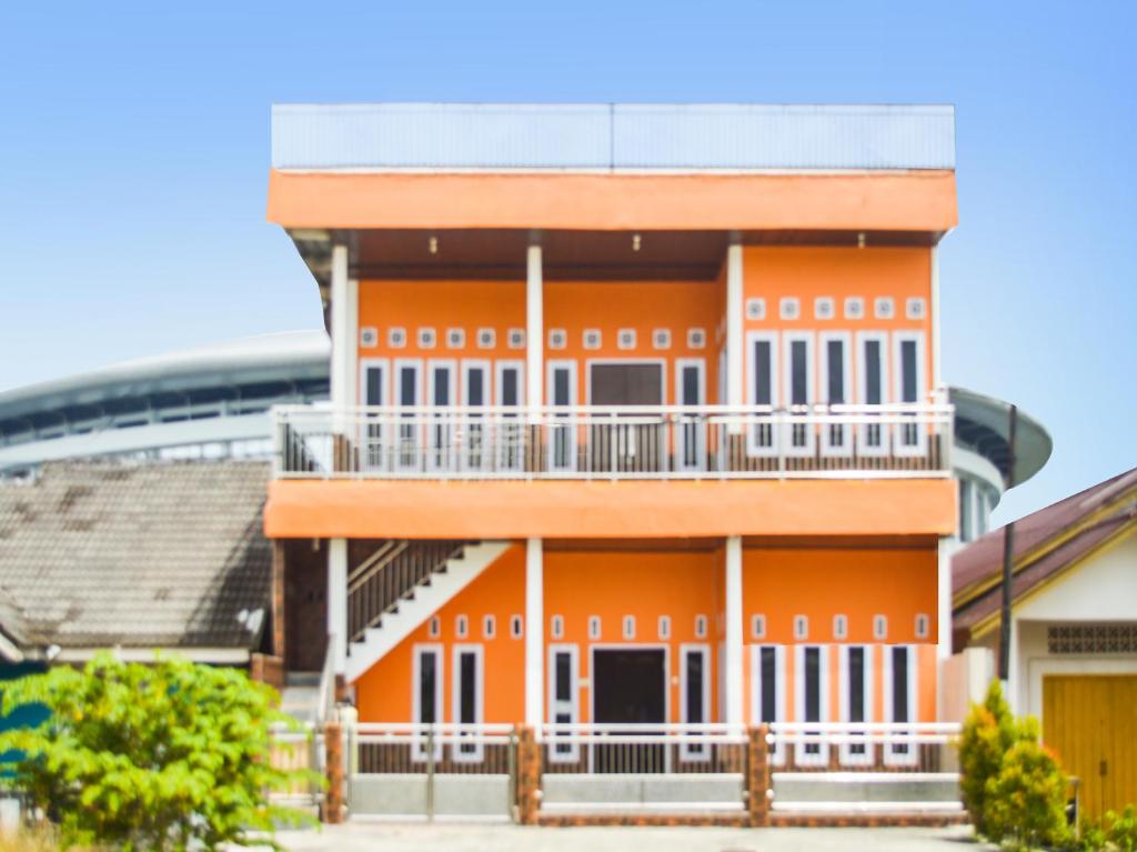 un bâtiment orange avec un balcon en face d'un stade dans l'établissement SPOT ON 91463 Obby Guest House, à Balikpapan