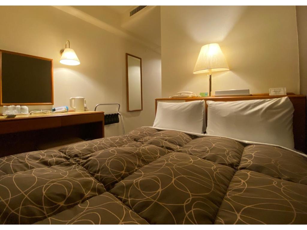 a bedroom with a bed and a desk and a television at Az Inn Fukui - Vacation STAY 65940v in Fukui