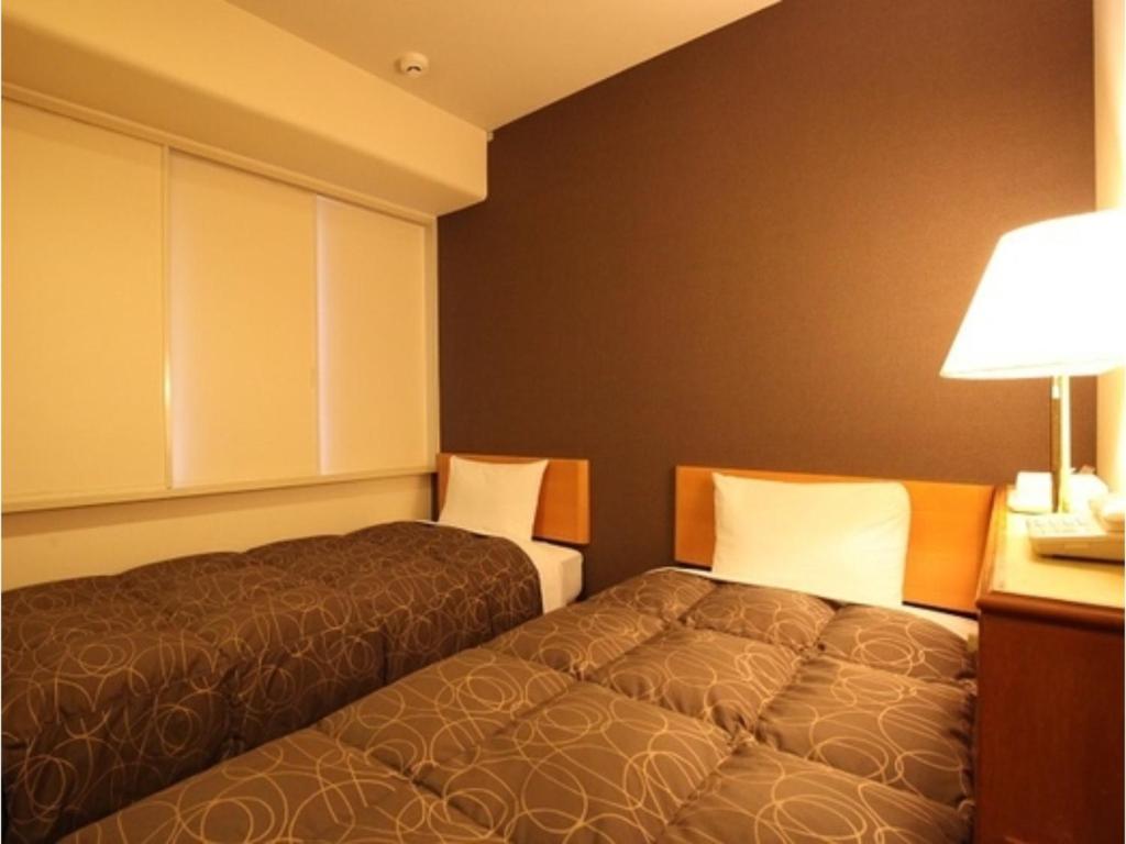 a hotel room with two beds and a lamp at Az Inn Fukui - Vacation STAY 65944v in Fukui