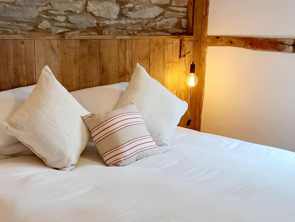 a bed with white sheets and pillows on it at Hay Barn, Penrheol Farm, Unique Barn Conversion in Builth Wells