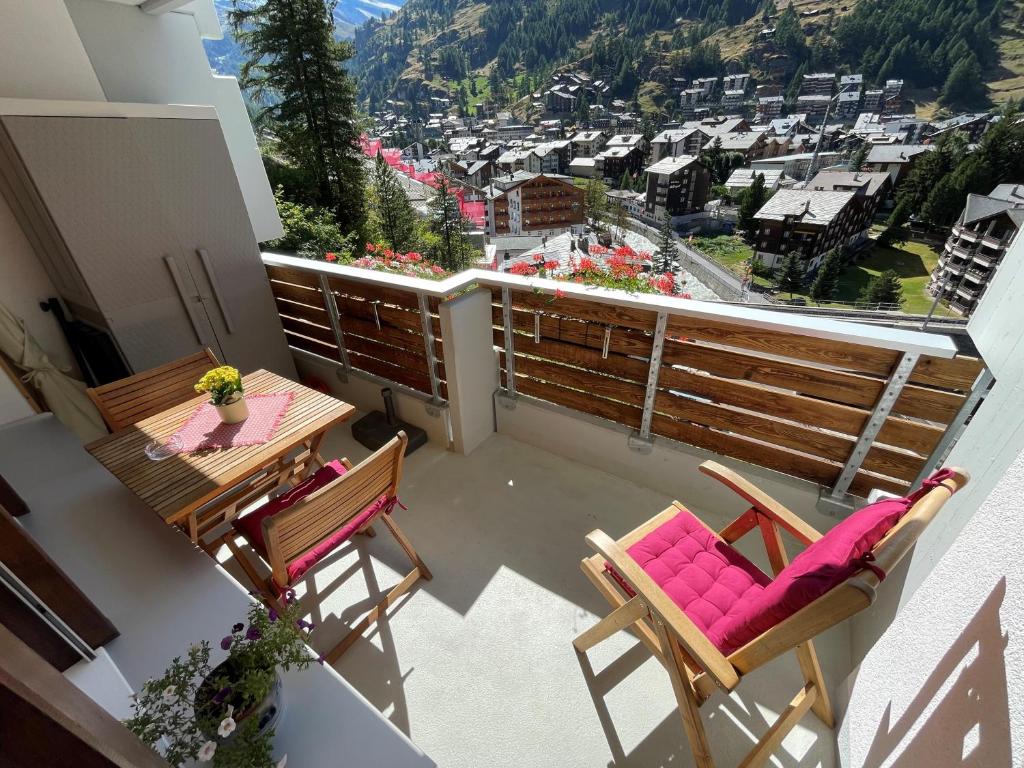 a balcony with a table and chairs and a view of a city at Haus Oasis in Zermatt