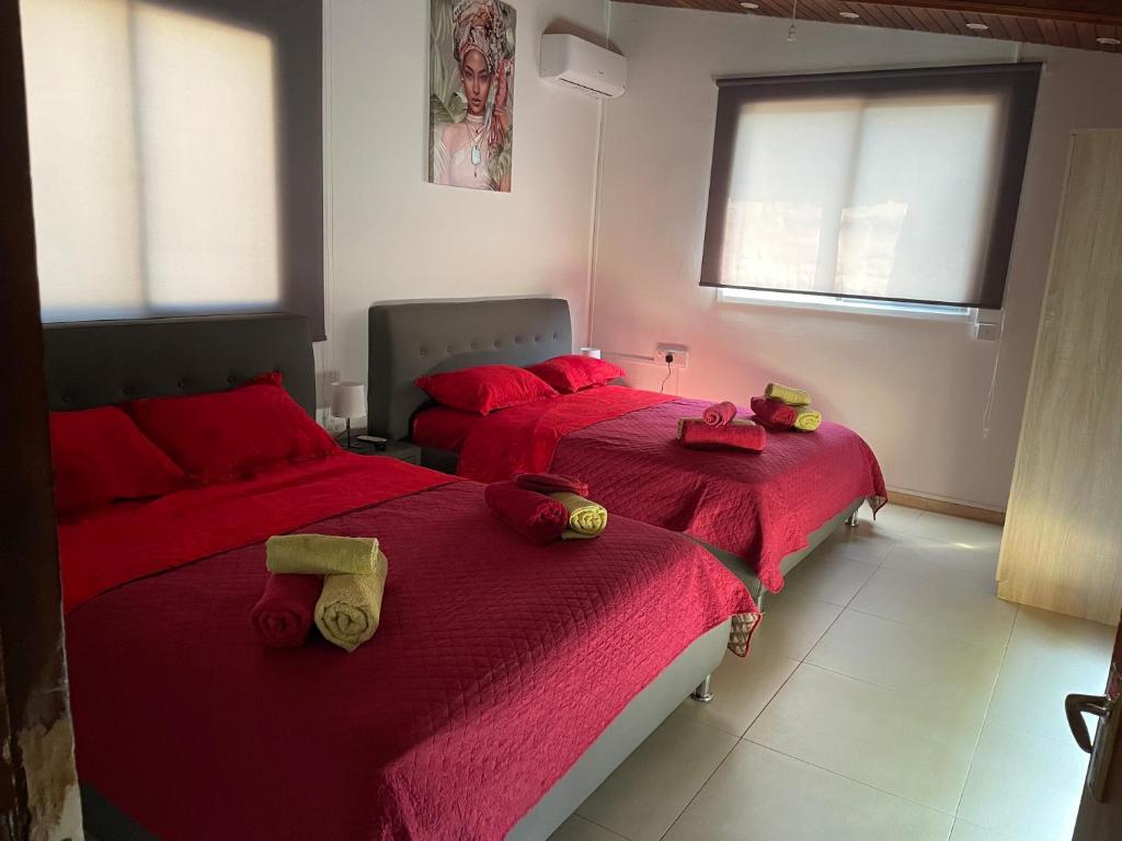 2 Betten in einem Schlafzimmer mit roter Bettwäsche und roten Kissen in der Unterkunft Sofros To Apomero 