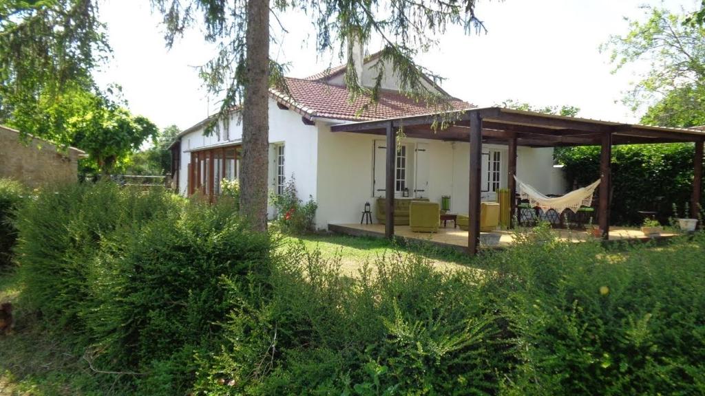 ein kleines weißes Haus mit einer Hängematte im Hof in der Unterkunft Maison indépendante sur grand terrain clos in Thénezay
