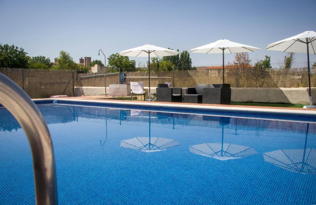 a swimming pool with chairs and umbrellas at Hostal-Casa Rural Rosa-Nonna in Sigüenza