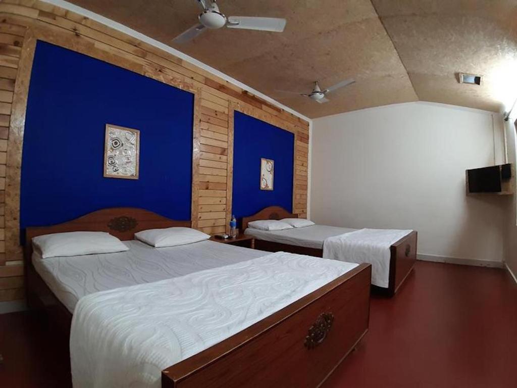 2 camas en una habitación con paredes azules en Royal Cottage, Anaimalai room, en Pollachi
