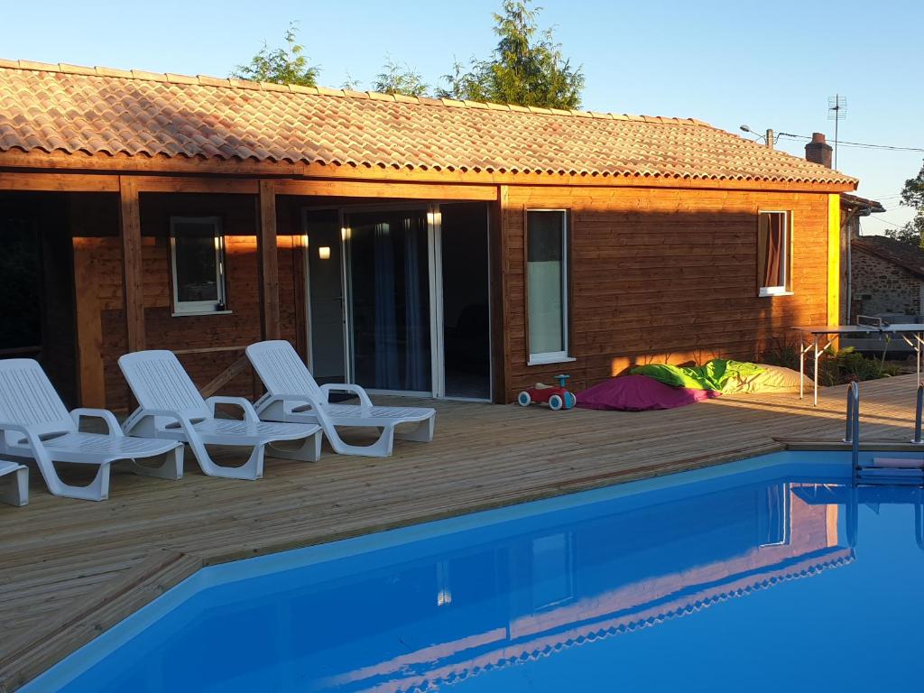 a house with a deck with chairs and a swimming pool at Le clos de lignac in Cieux