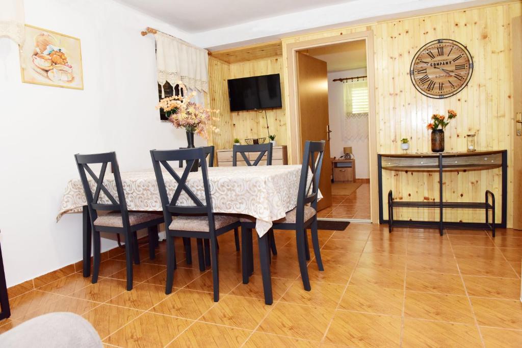 une salle à manger avec une table, des chaises et une horloge dans l'établissement Apartman Bingo, à Josipdol