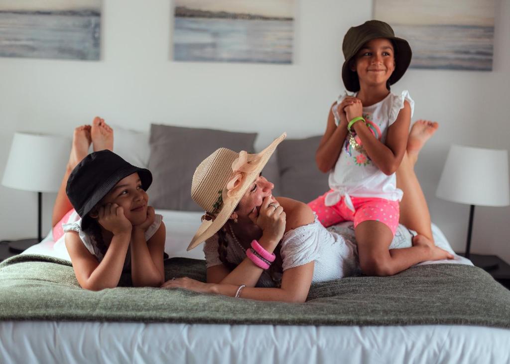 聖胡安的住宿－Old San Juan Rentals，三个孩子躺在床上戴帽子