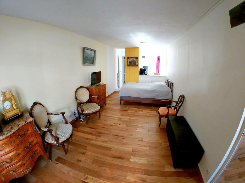 Appartement en plein cœur de Milly-la-Forêt في ميلي-لا-فوريه: غرفة نوم بسرير وكراسي في غرفة