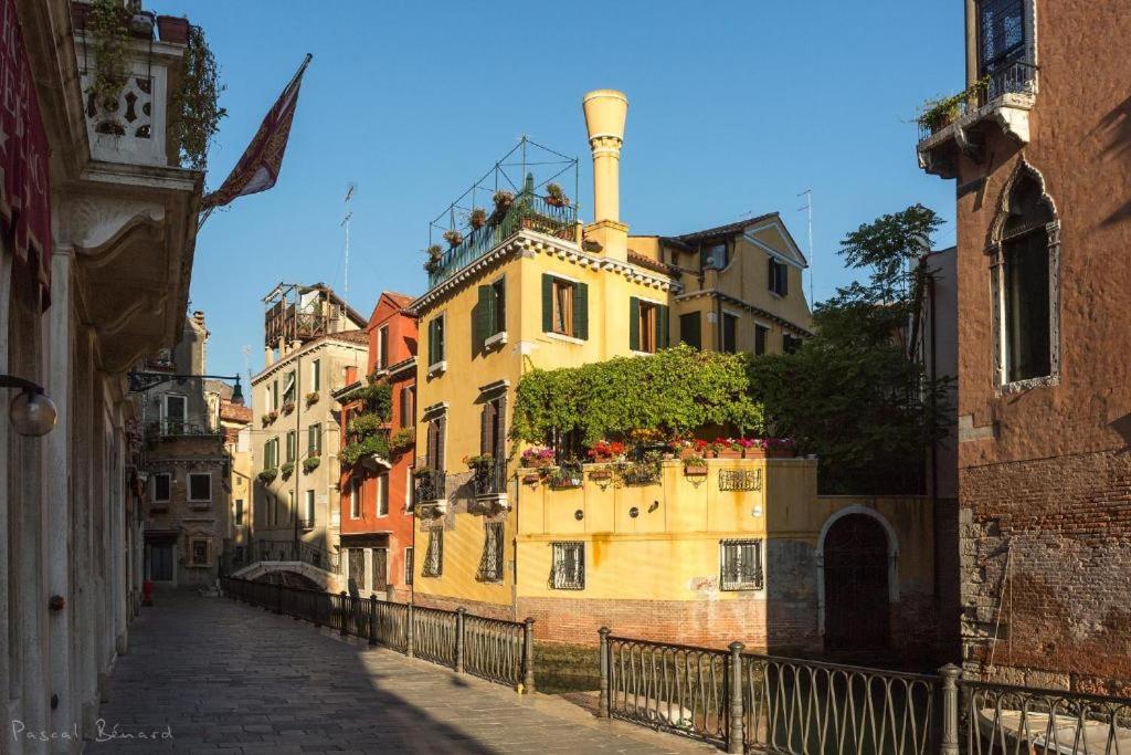 an alley with a yellow building with plants on it at Residenza de l'Osmarin Suites in Venice