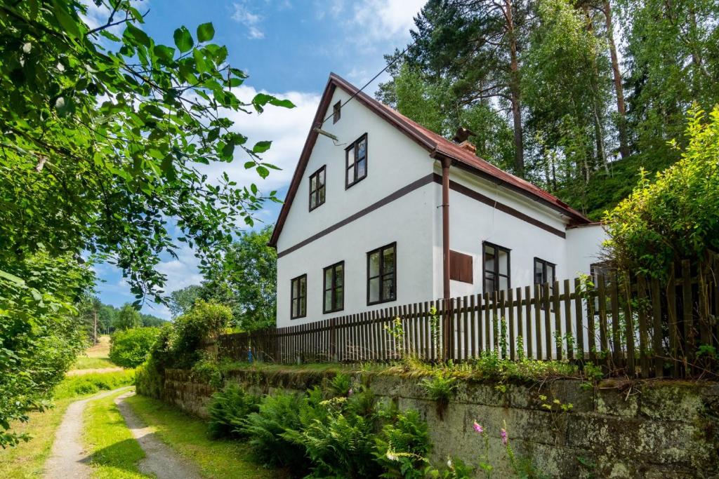 una casa blanca con una valla y árboles en Chalupa Mařenice, en Mařenice