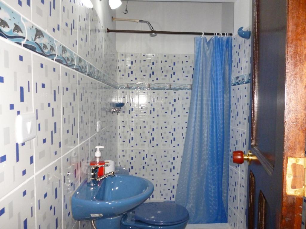 y baño con lavabo azul y aseo. en Hostal Mirador Andino en Manizales