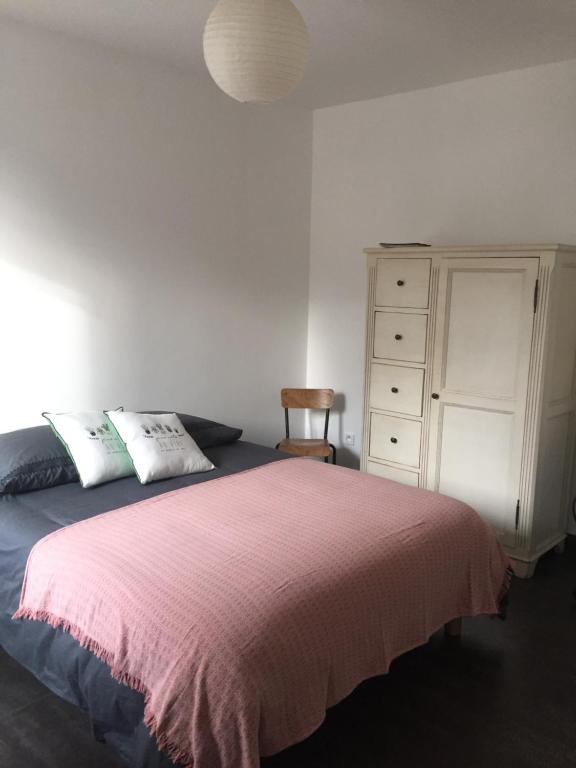 a bedroom with a bed with a pink blanket and a dresser at Chez MB in Bastelicaccia