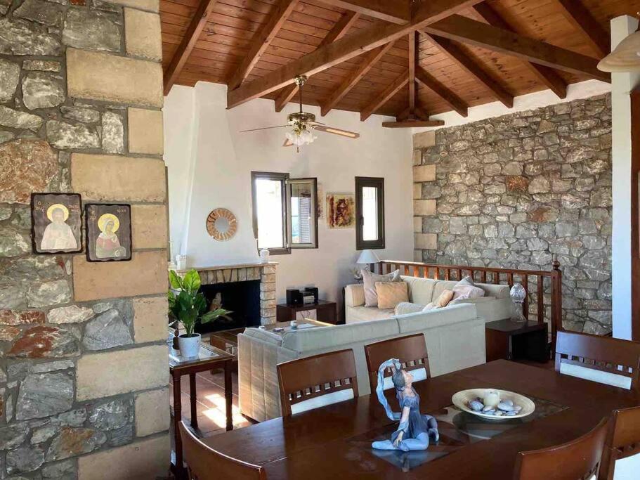 sala de estar con mesa y pared de piedra en Nikkis house in Stoupa, close to all amenities, en Stoupa