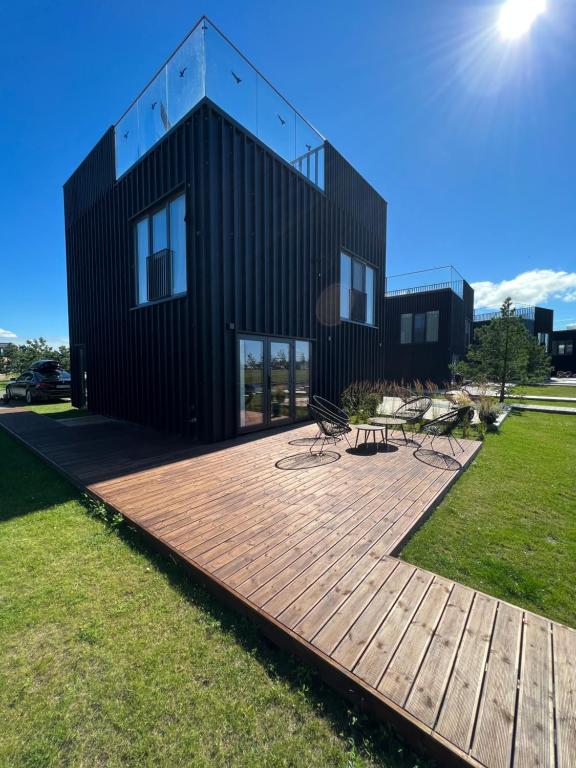 une maison avec une terrasse en bois devant elle dans l'établissement Svencele Lounge Apartments, à Svencelė