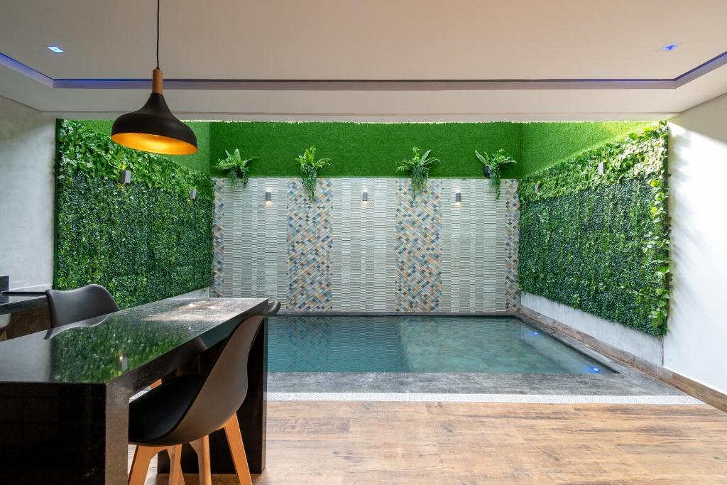 an indoor pool with a green wall with plants at Drops Motel Manaus in Manaus
