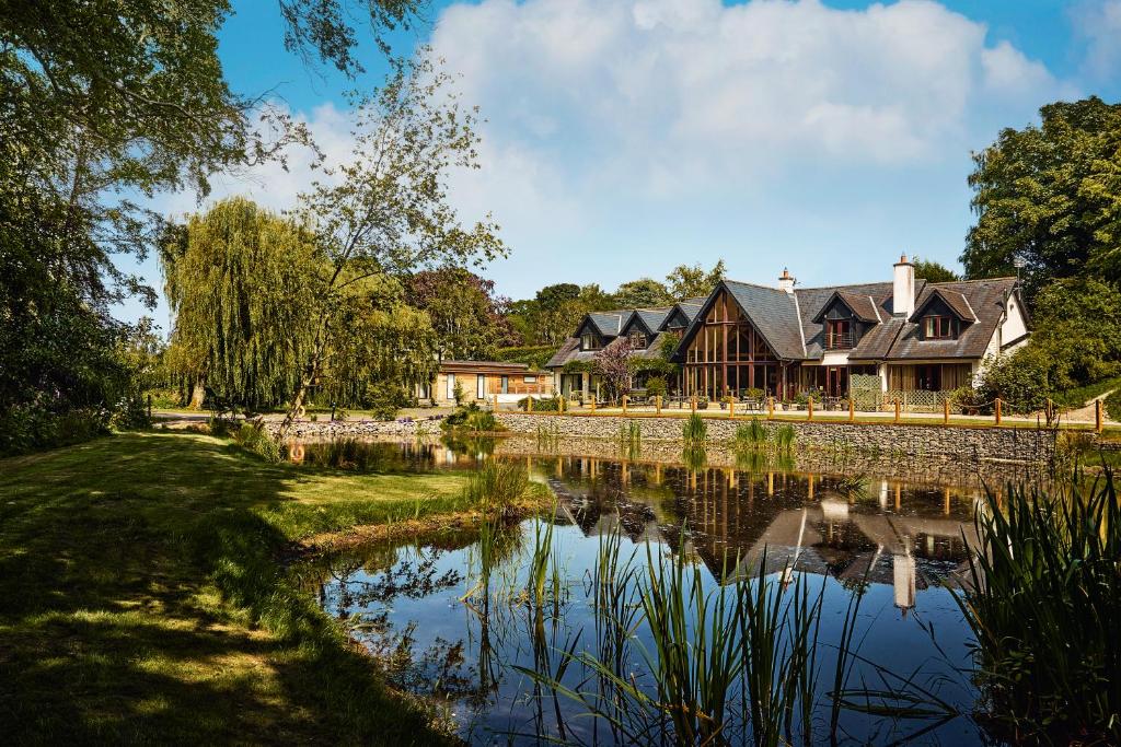 ein Haus mit einem Teich davor in der Unterkunft Willowbeck Lodge Boutique Hotel in Carlisle