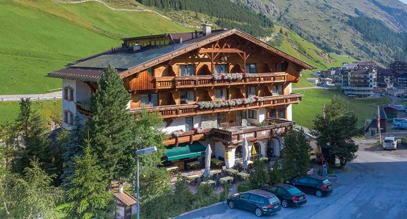 Hotel Alt Vent Tyrol في فنت: منزل خشبي كبير فيه سيارات متوقفة أمامه