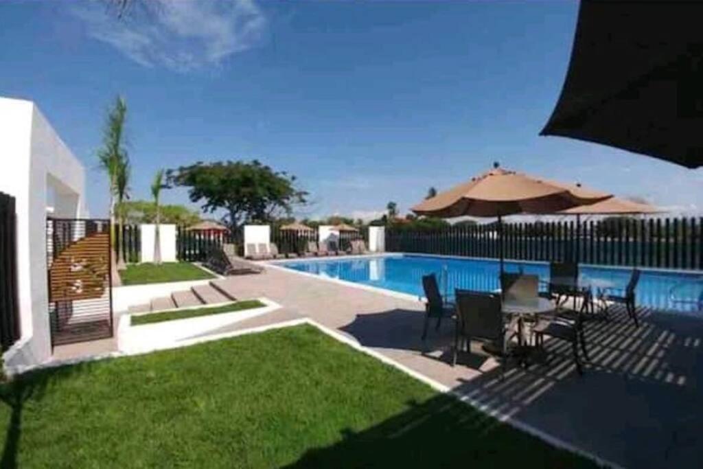 a pool with a table and chairs and an umbrella at Hacienda en Primavera, descanso Familiar total in Puerto Vallarta