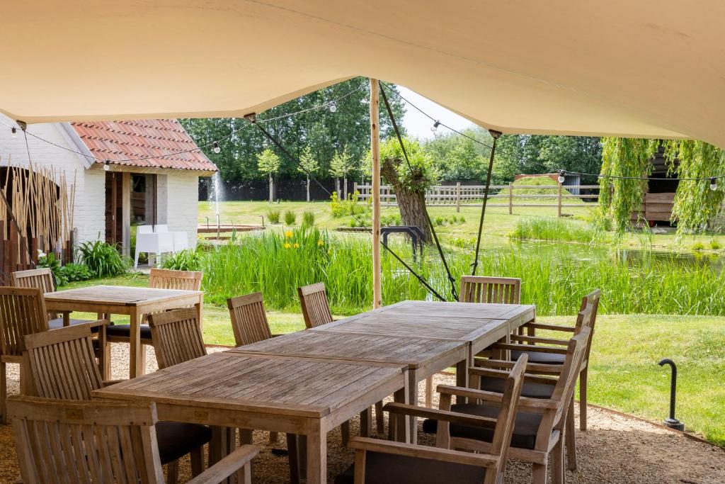 a wooden table and chairs under a tent at B&amp;B Leonie in Alveringem