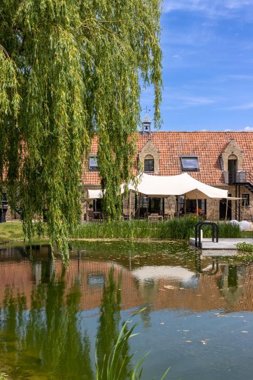 a building with a tent next to a pond at B&amp;B Leonie in Alveringem