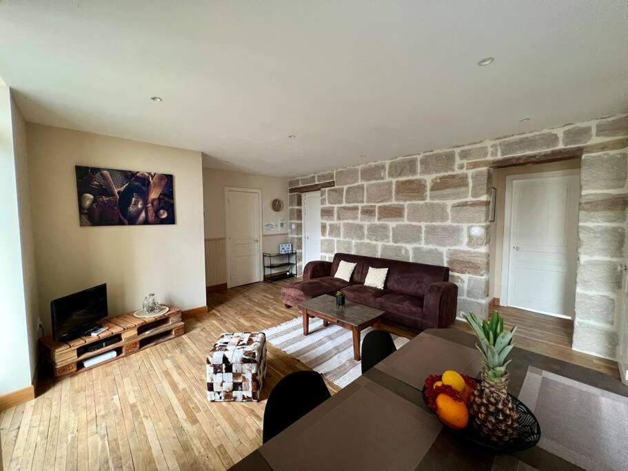 ein Wohnzimmer mit einem Sofa und einer Steinmauer in der Unterkunft Casa Zola - Magnifique T3 Climatisé - Centre Ville in Brive-la-Gaillarde