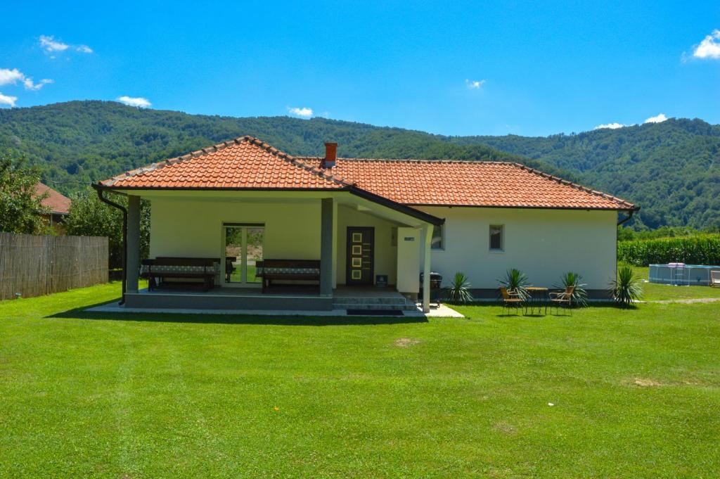 a small house with a green lawn in front of it at Drinska kućica in Ljubovija