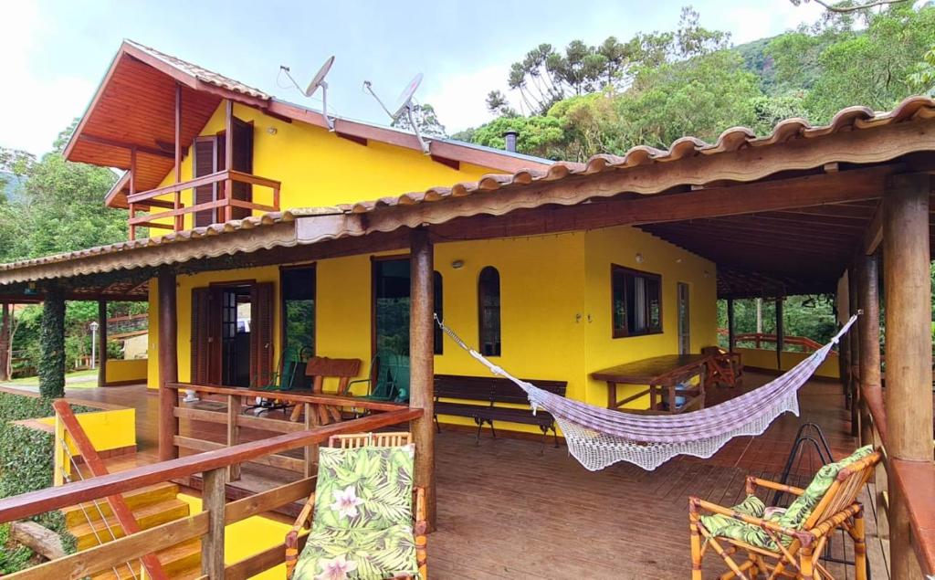 uma casa amarela com uma rede num deque em Chacara Diniz São Francisco Xavier em São José dos Campos