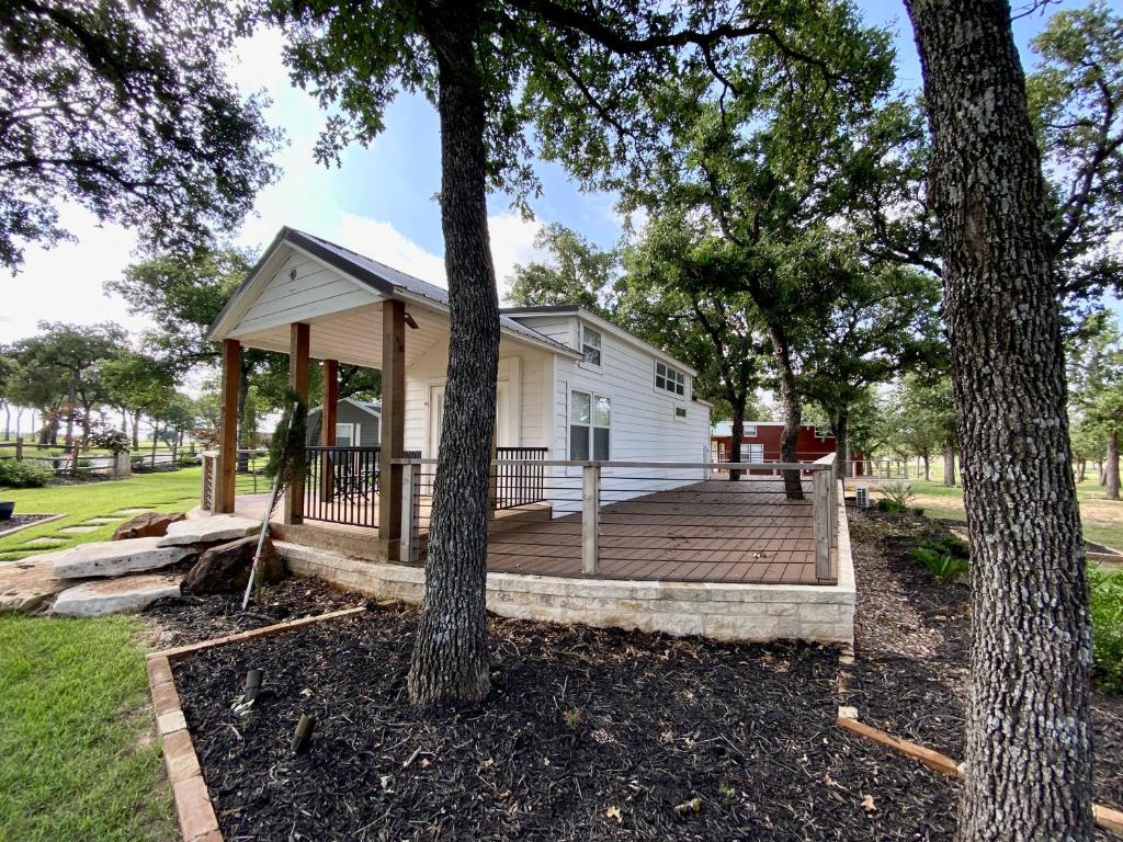 a small white house with a porch and two trees at Farmhouse Style Tiny Home with Patio - 4 mi to Town in Fredericksburg